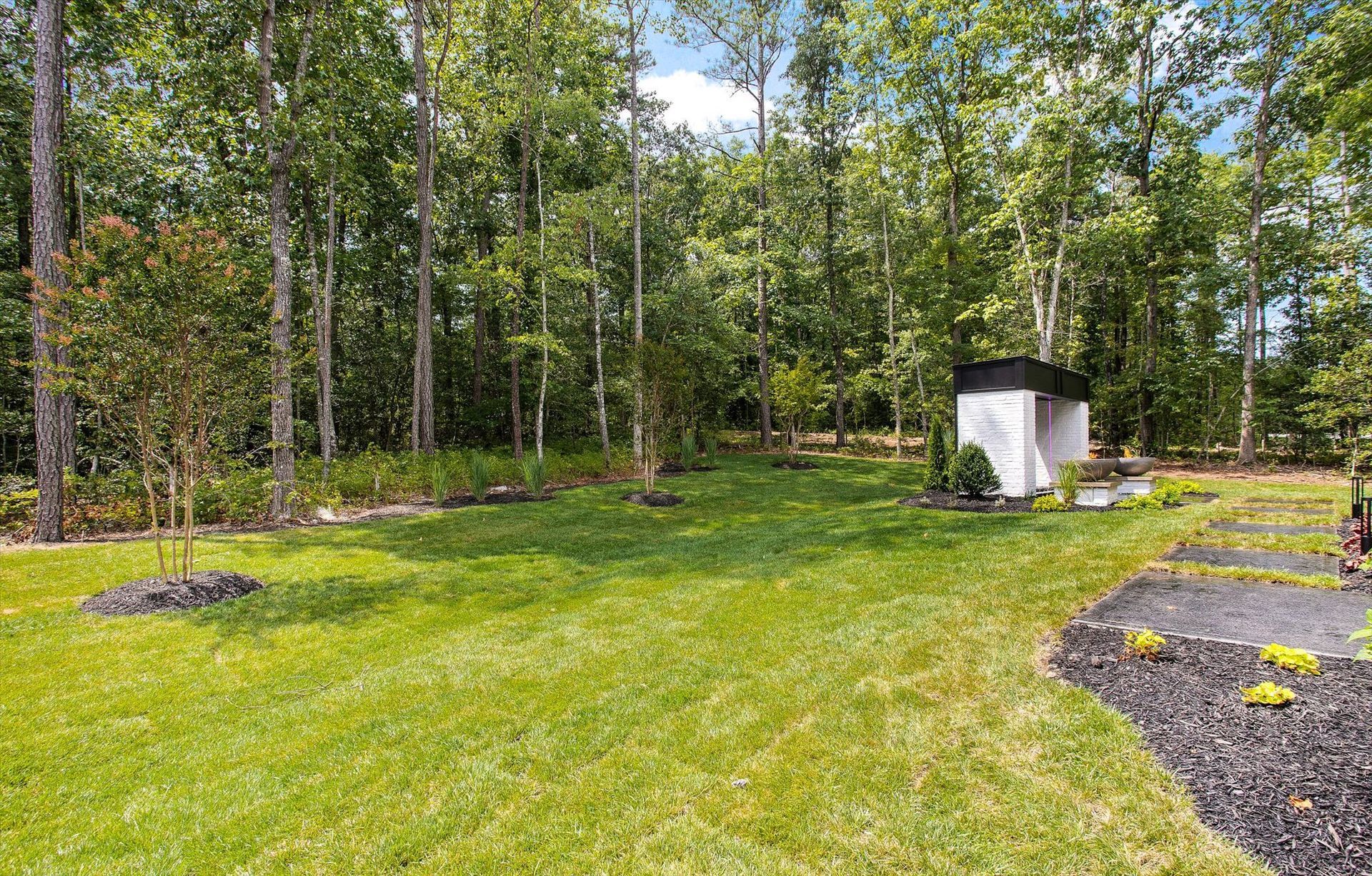 There is a shed in the middle of a lush green field surrounded by trees.