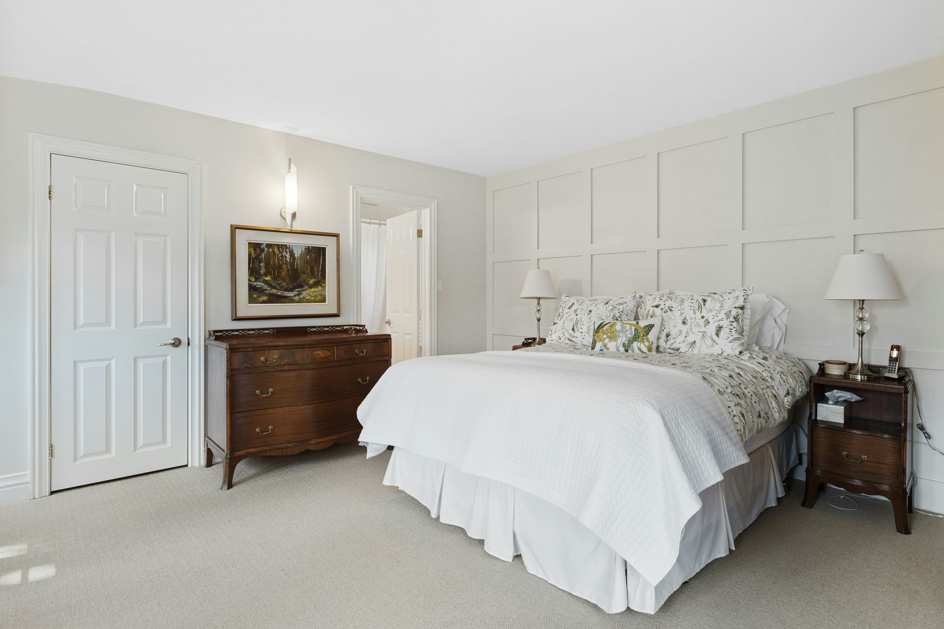 Bright white bedroom with a large bed, dresser, and nightstand