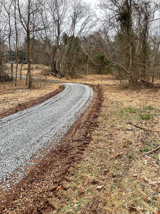 Curving gravel path through a leafless wooded area on a gray day