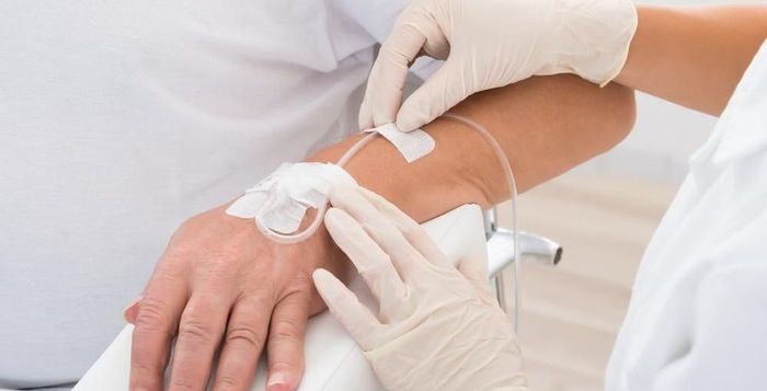 Nurse inserting an IV into a patient’s arm with a gloved hand in a clinical setting