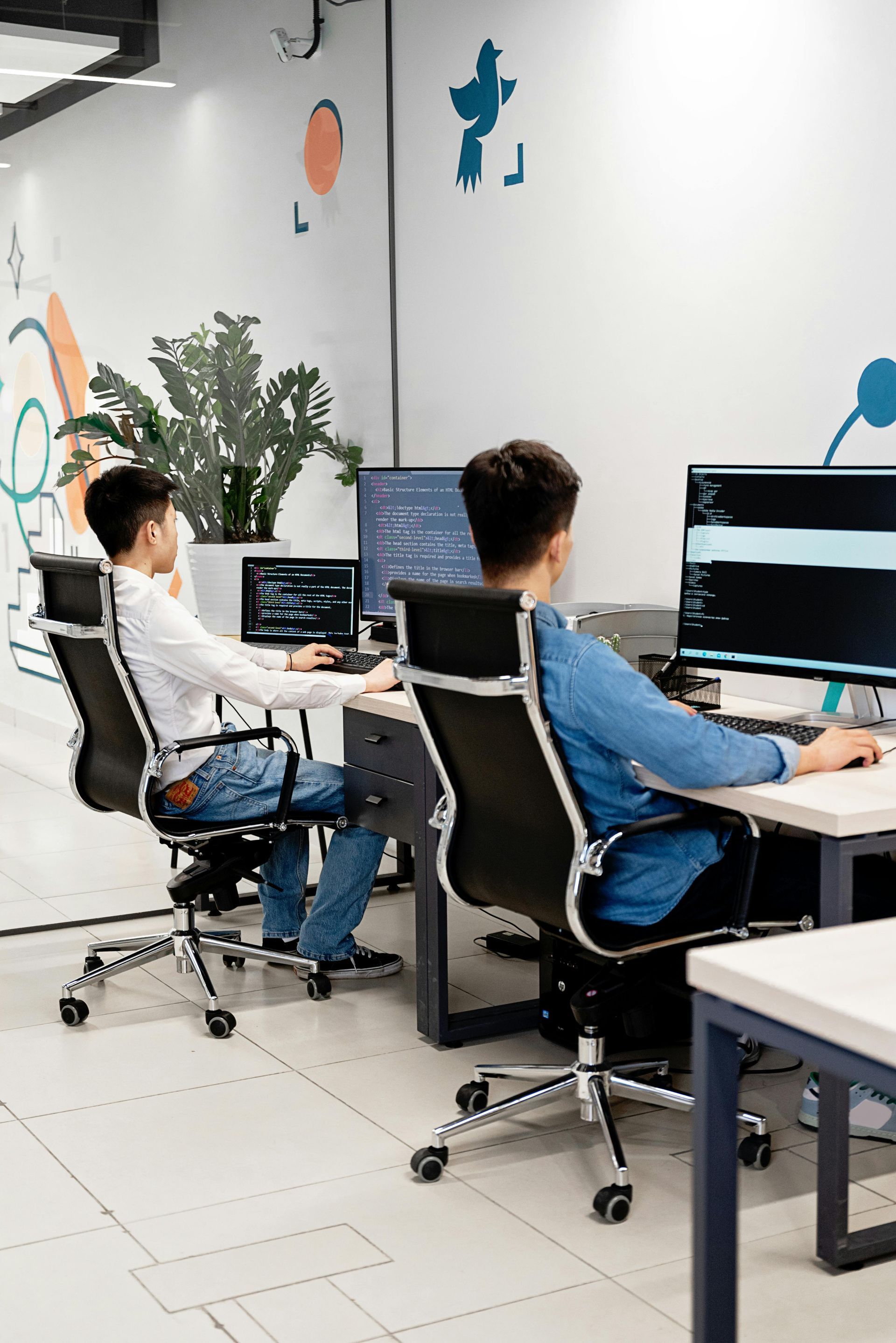 Business team at a conference table with laptops; smiling and looking at the camera in a bright office.