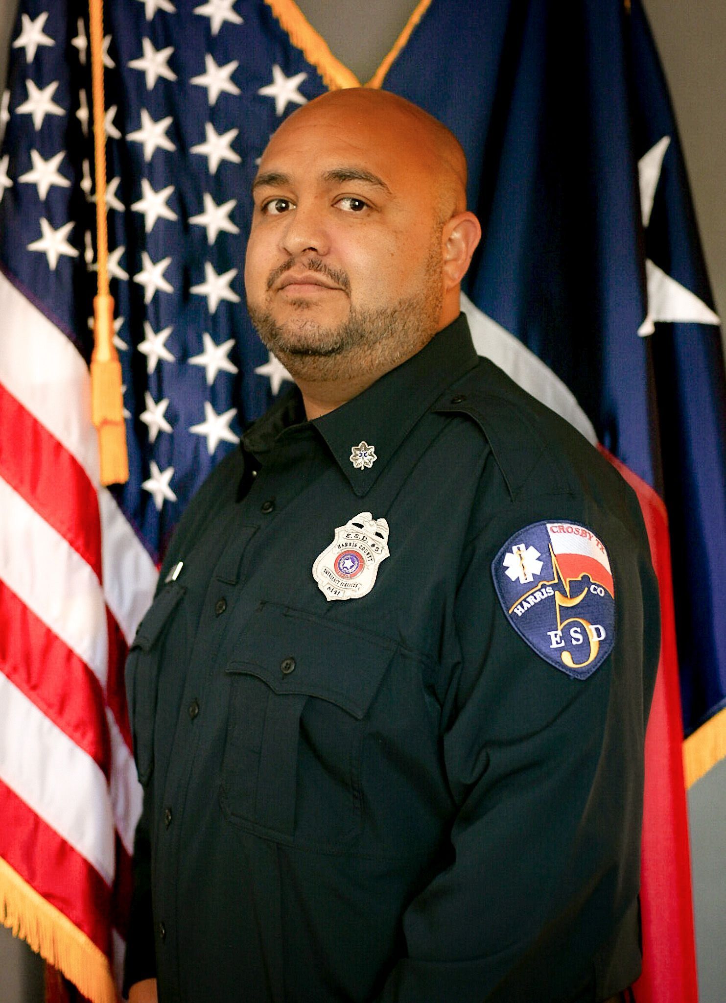 A man in a fire uniform is standing in front of an American flag