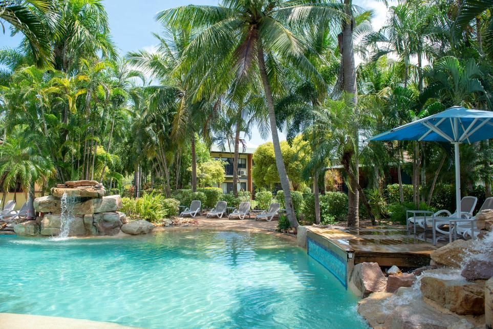 A Large Swimming Pool Surrounded by Palm Trees and Chairs — Figleaf Pool Products in Coconut Grove, NT