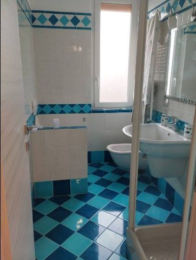 Un bagno con piastrelle blu e bianche e una finestra