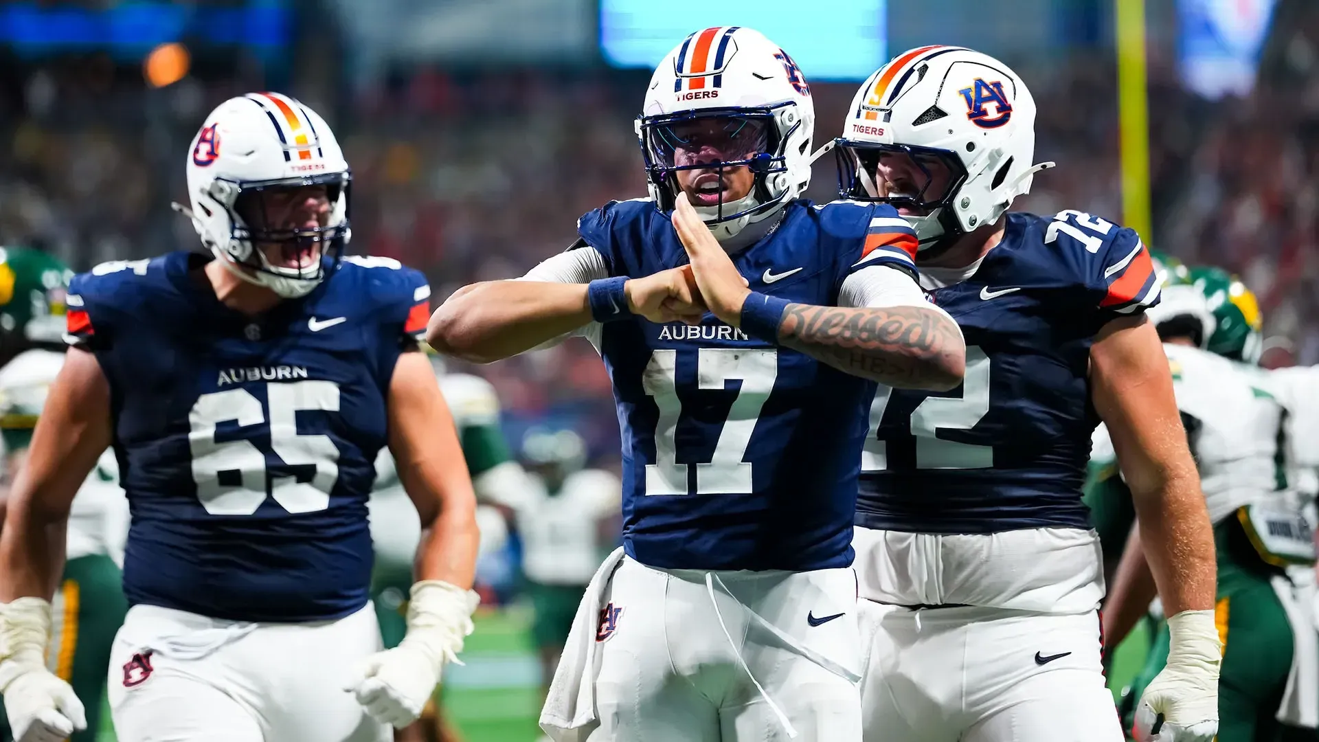 Three Auburn football players celebrate on the field during AFLAC kickoff game September 2026