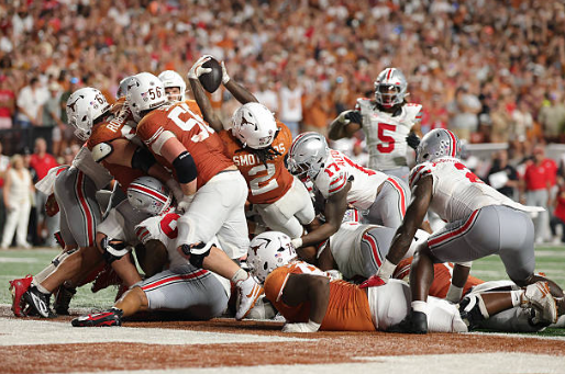 Football players pile up in a goal-line scrum near the end zone.
