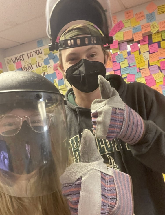 Mother and daughter in protective gear giving thumbs up in a rage room charlotte nc with colorful sticky notes