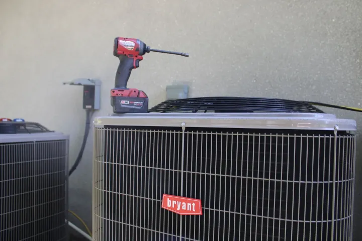 A drill is sitting on top of a bryant air conditioner.