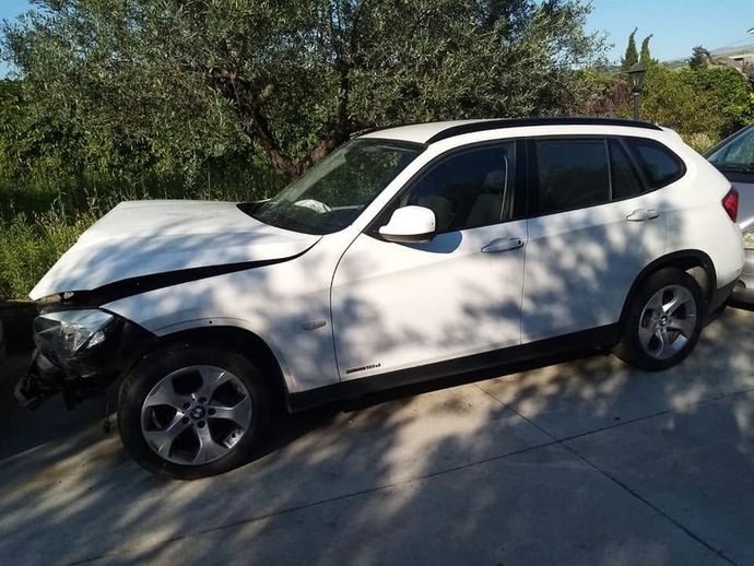 SUV bianco con danni alla parte anteriore sinistra parcheggiato in un vialetto in pieno giorno