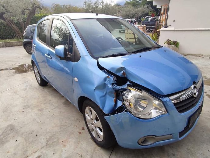 Auto blu con danni alla parte anteriore sinistra parcheggiata in un vialetto.