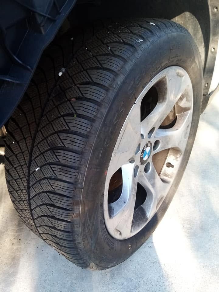 Pneumatico sgonfio su un cerchione argentato di un'auto, con danni visibili al fianco del pneumatico.