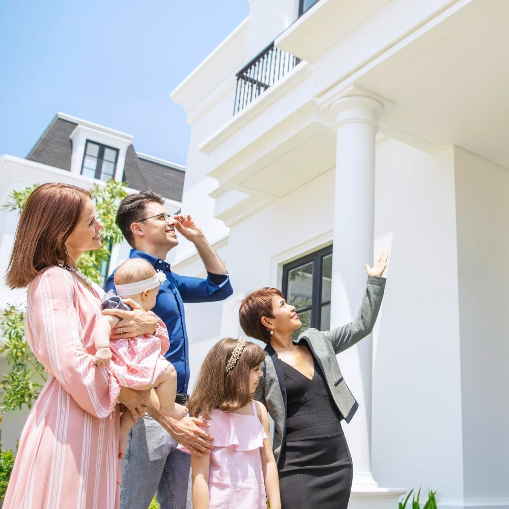 Family looking at a white house with a realtor; a sunny day.