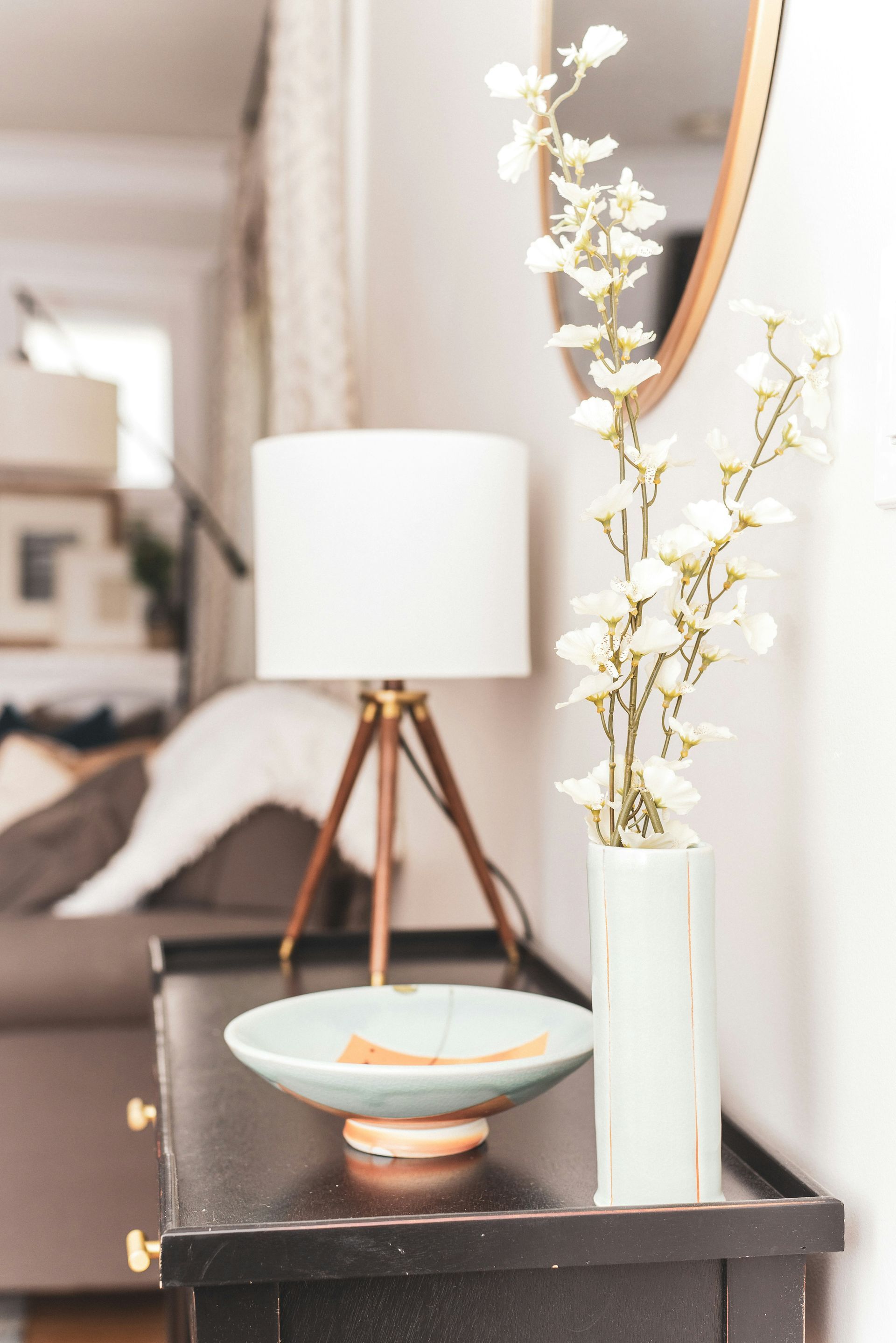 A vase of flowers is sitting on a table next to a lamp.