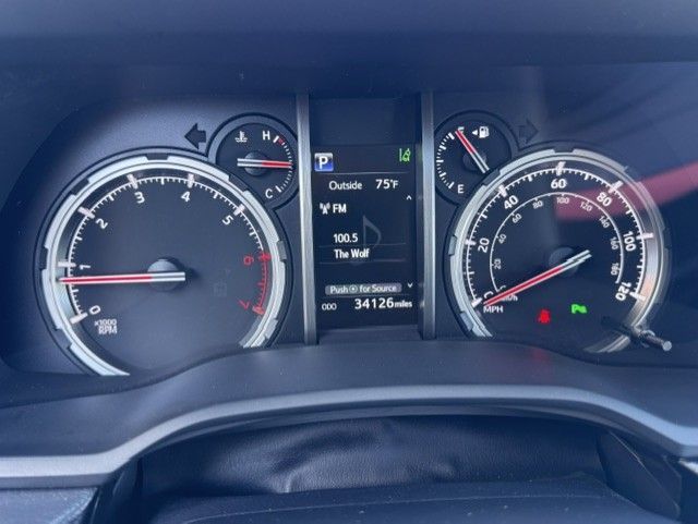 Car dashboard with illuminated speedometer, tachometer, and digital display showing fuel, temperature, and mileage.