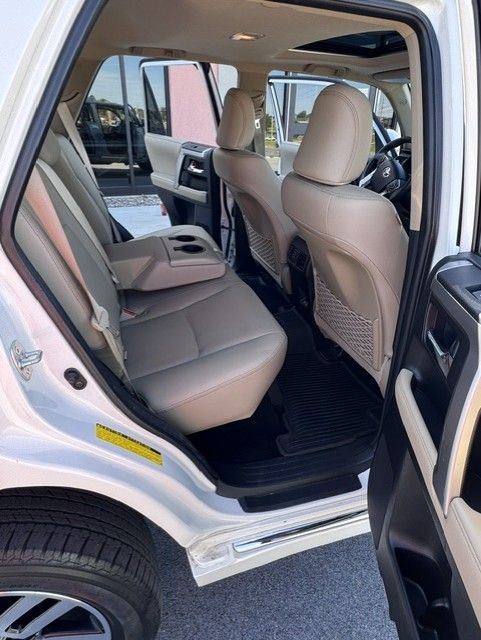 Open rear door of a white SUV, showing beige interior seating and cargo area.