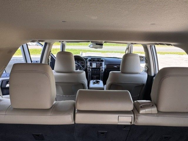 Interior of an SUV, showing three rows of beige seats and the dashboard from the back cargo area.