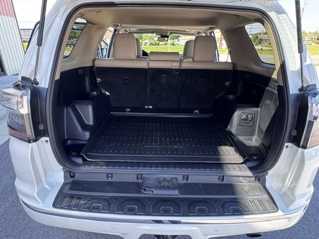 Open SUV trunk with folded rear seats and black cargo area in a white vehicle