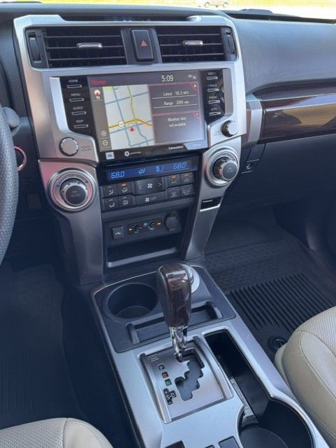 Car dashboard with navigation screen, climate controls, and gear shift in a beige interior.