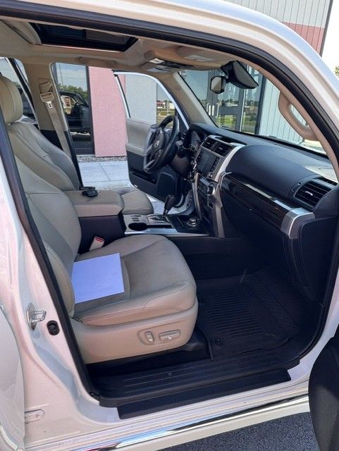 Open car door showing beige leather interior and dashboard, with a folder on the driver’s seat