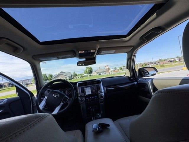 Car interior with panoramic sunroof, front seats, and view of a road and blue sky outside.