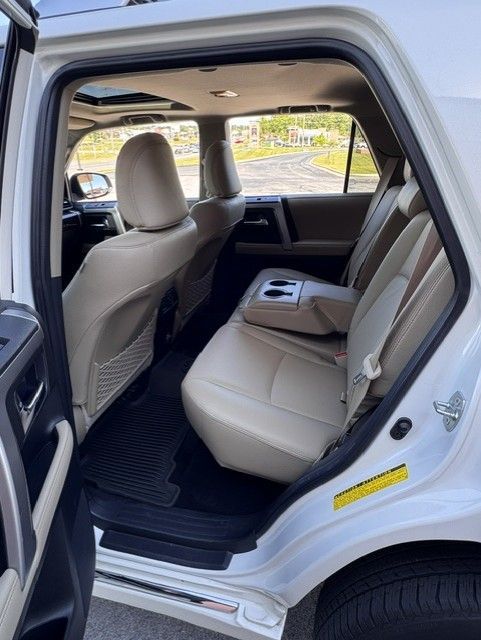 Open car door showing beige rear seat and black floor mats in a white SUV