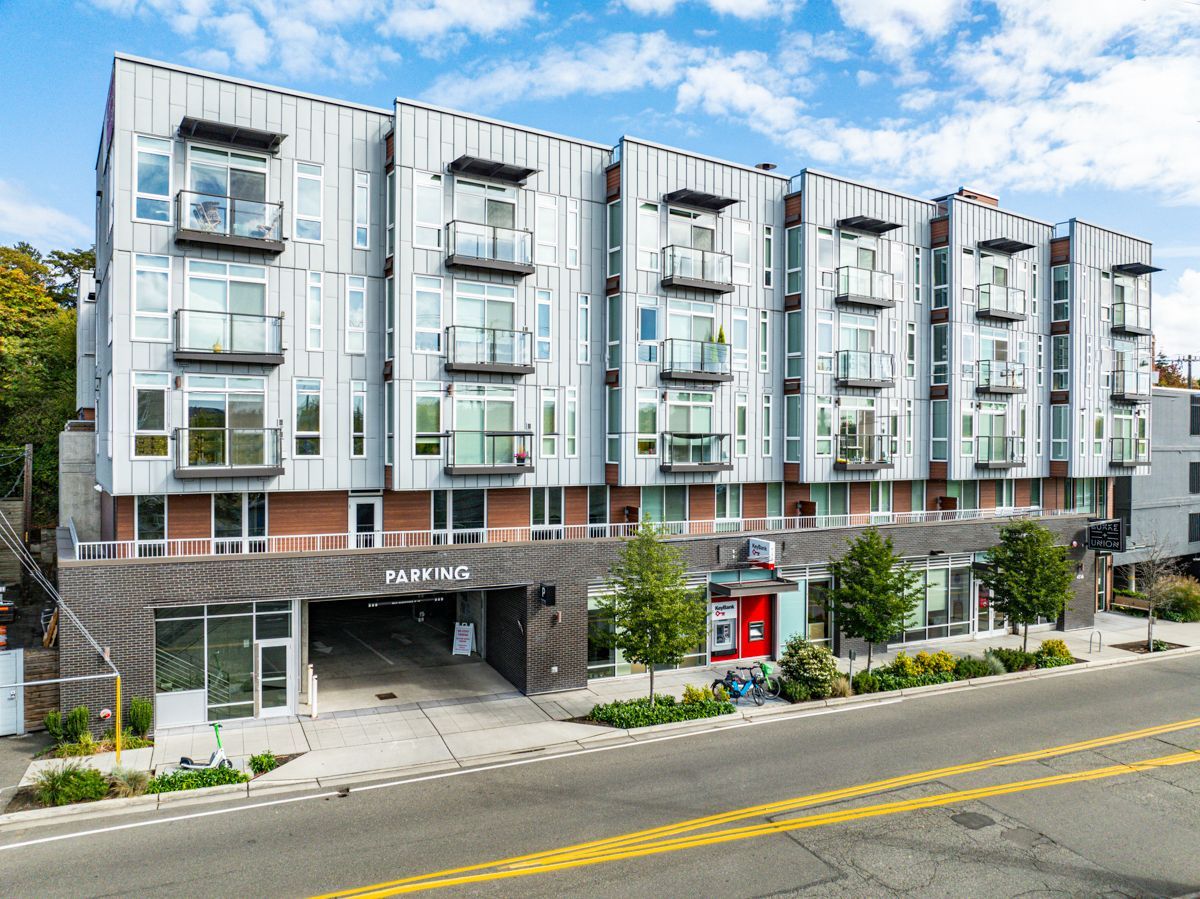 Modern apartment building with balconies and ground-floor retail on a city street