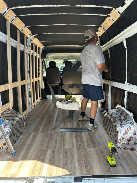 Person installing wood paneling inside a van conversion.