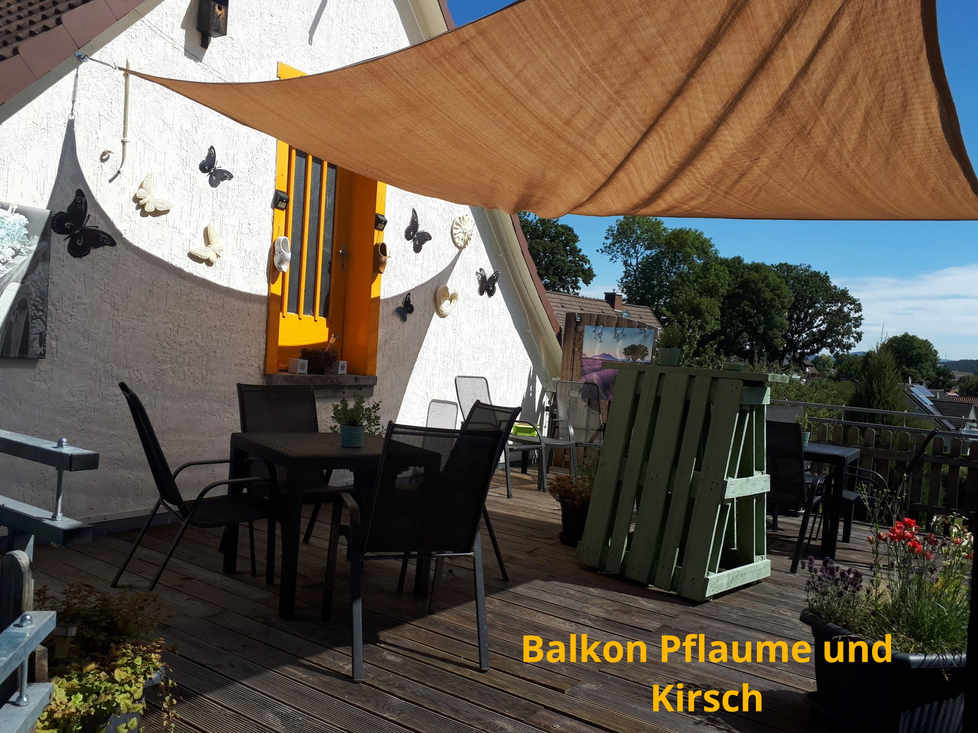 Balkon met tuinmeubilair, parasol en potplanten, met uitzicht op de stad.