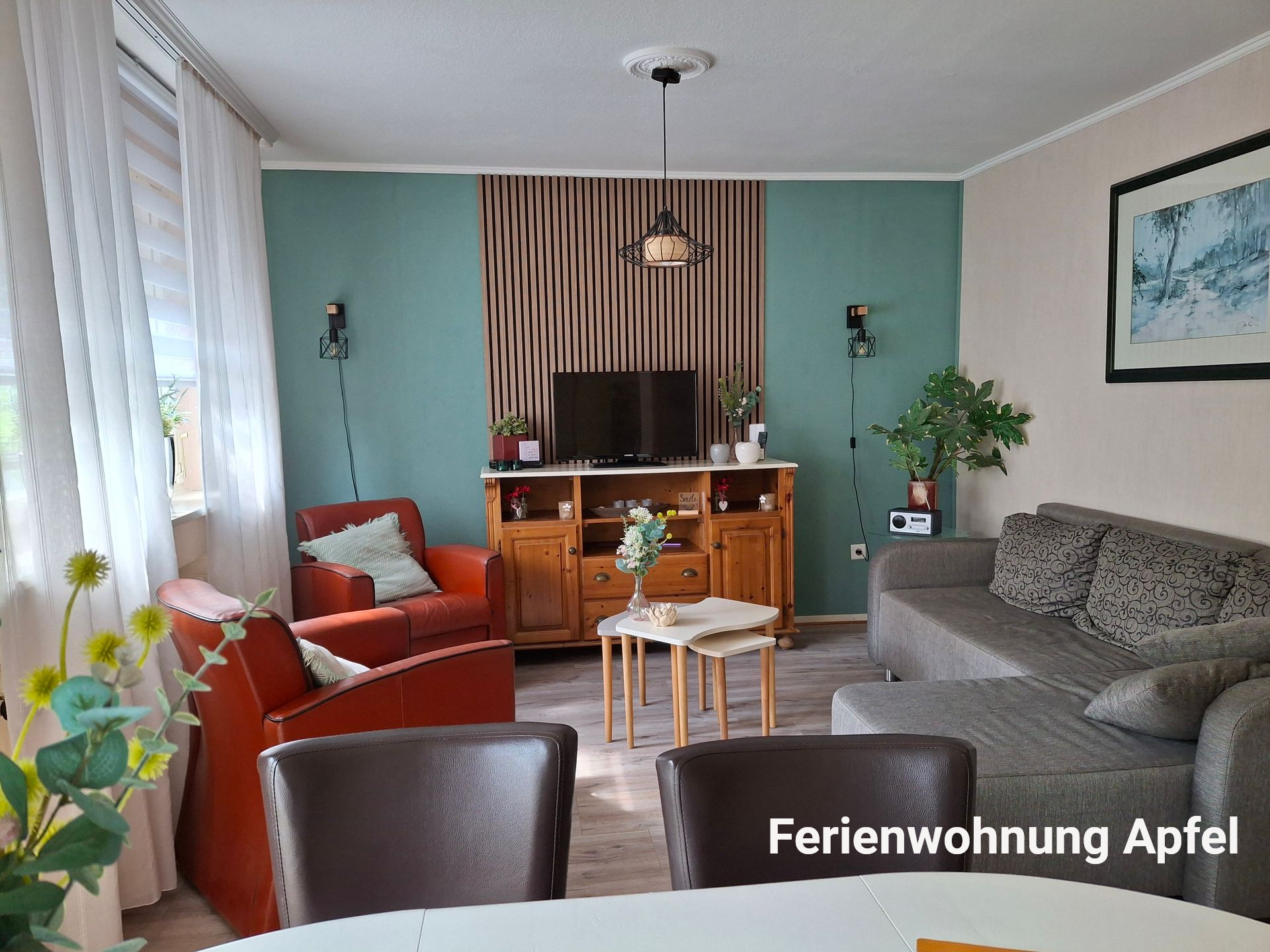 Woonkamer met een turquoise accentmuur, houten lambrisering, een oranje stoel en een grijze hoekbank.