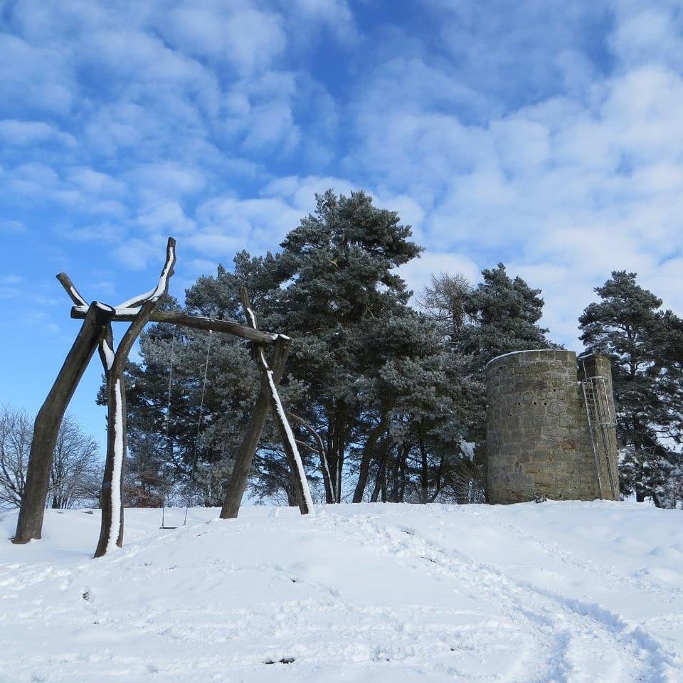 De warte, landschap met een stenen toren en een houten constructie tegen een blauwe hemel.