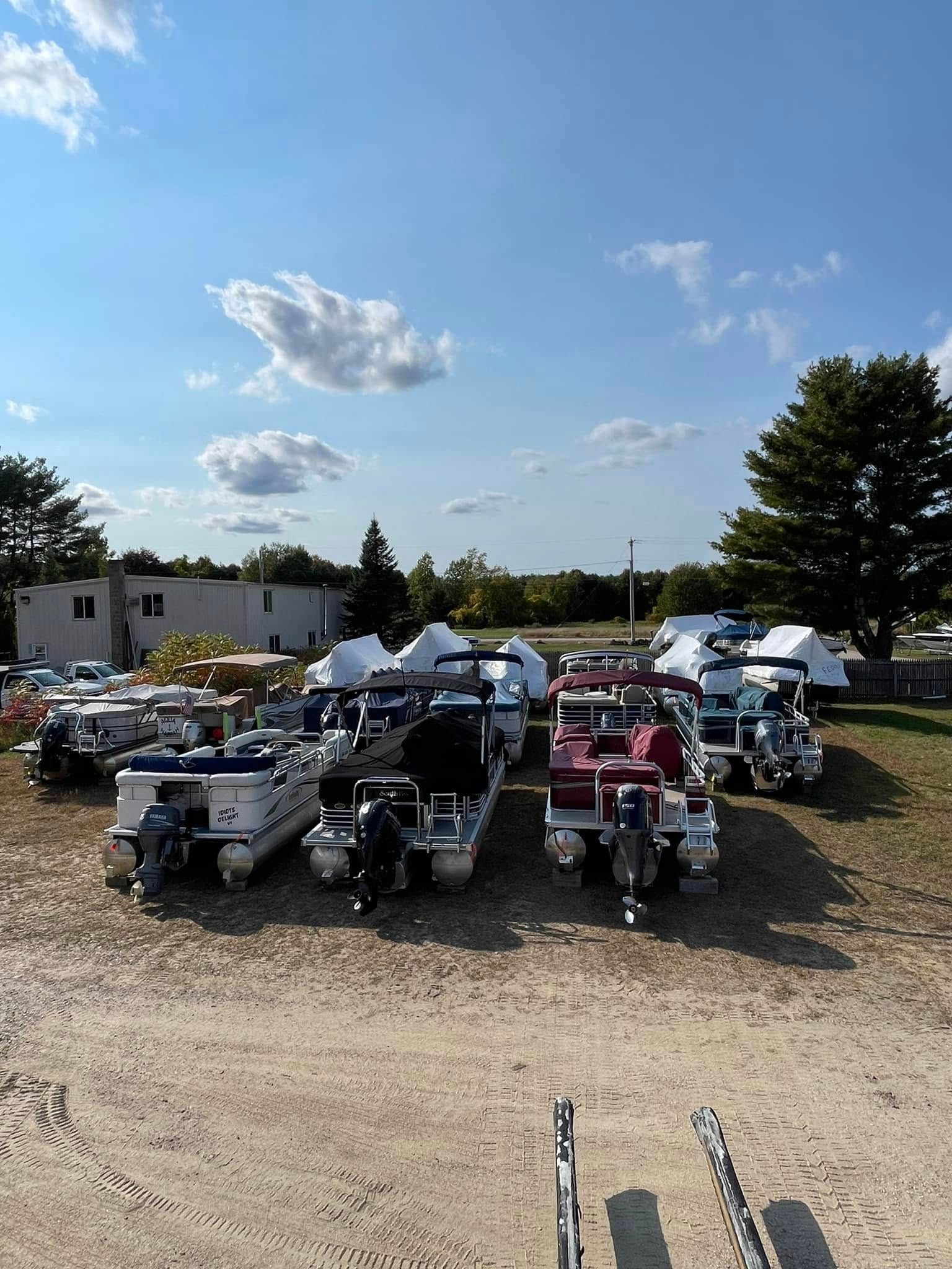 A bunch of pontoon boats are parked in a lot