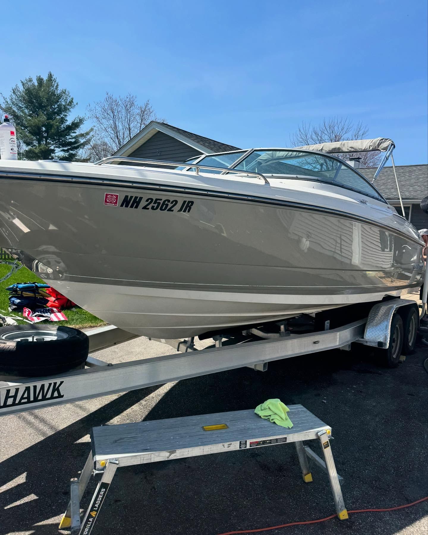 A boat is parked on a trailer with a license plate that says hawk.