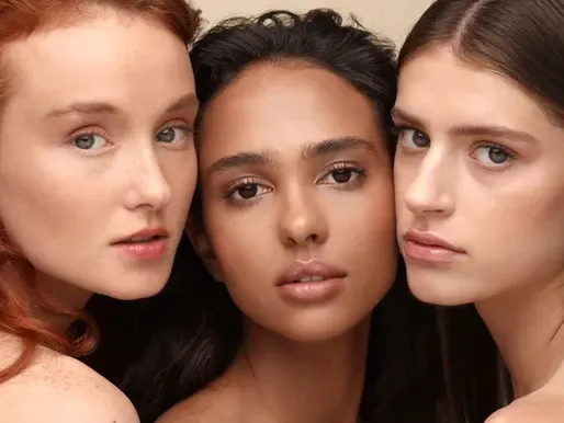 Three women of different races are posing for a picture together.