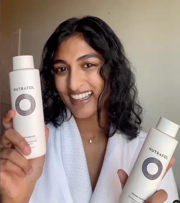 A woman in a white robe is holding two bottles of lotion.