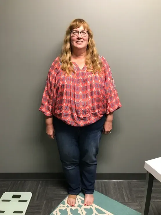 A woman in a plaid shirt and jeans is standing on a mat.