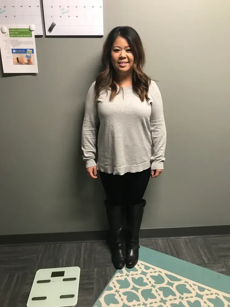 A woman is standing next to a scale in a room.