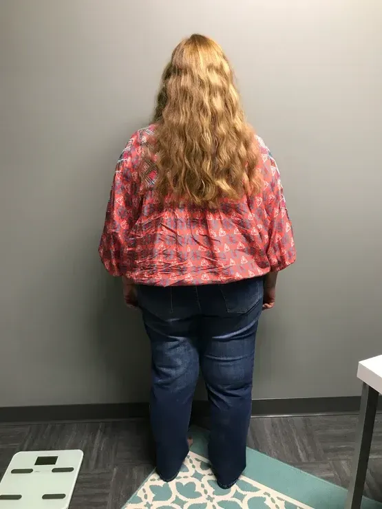 A woman with long hair is standing in front of a wall.