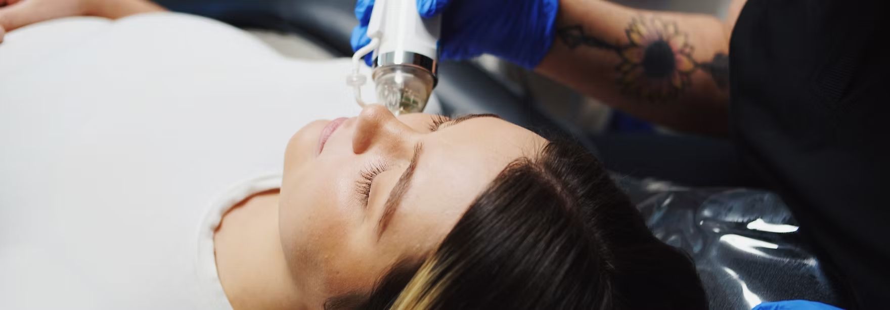 A woman is getting a tattoo on her face.