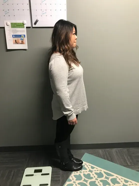 A woman is standing next to a scale in a room.