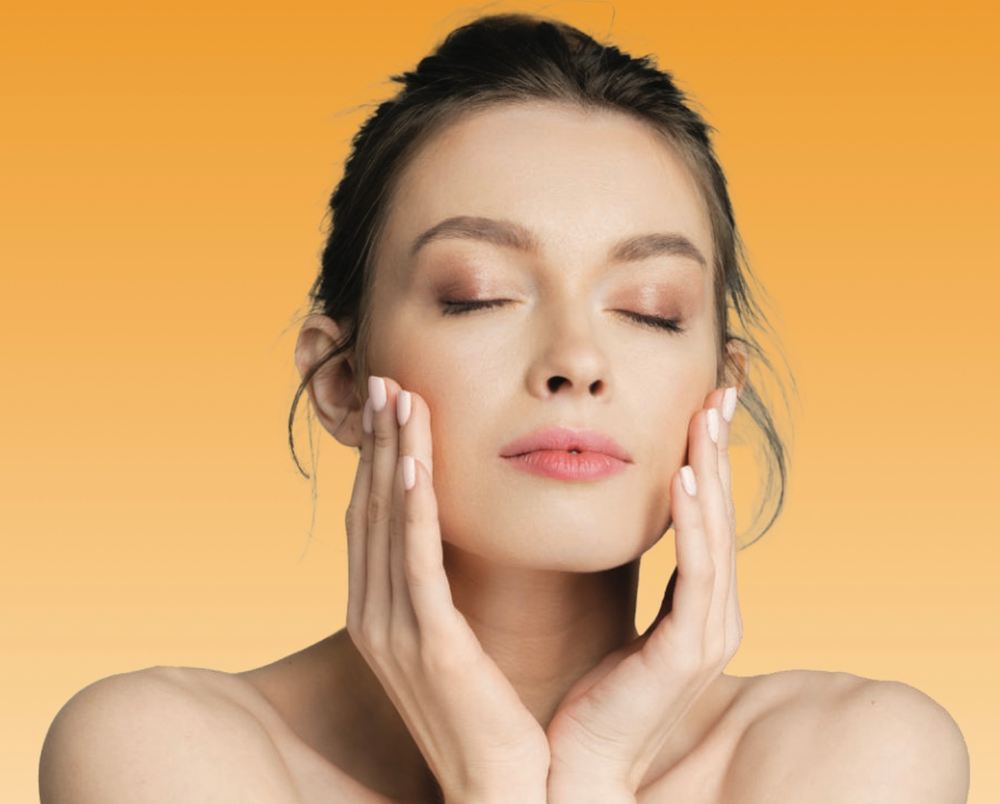 Woman with eyes closed, hands on cheeks, against a yellow-orange background.