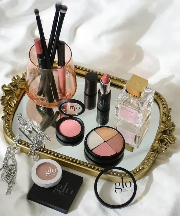 A tray of makeup including a bottle of glo perfume