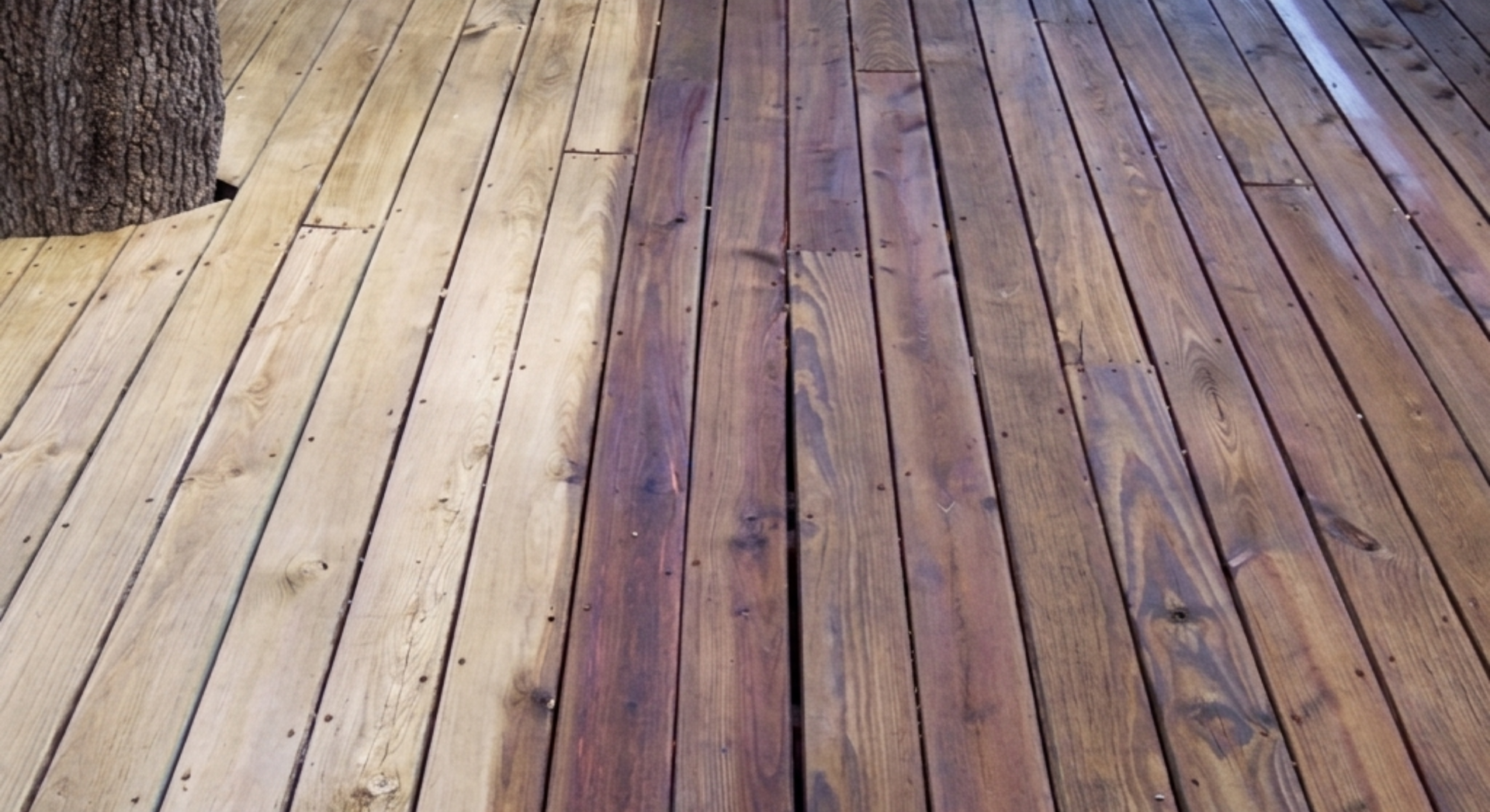 Partially stained wooden deck showing light and dark boards.