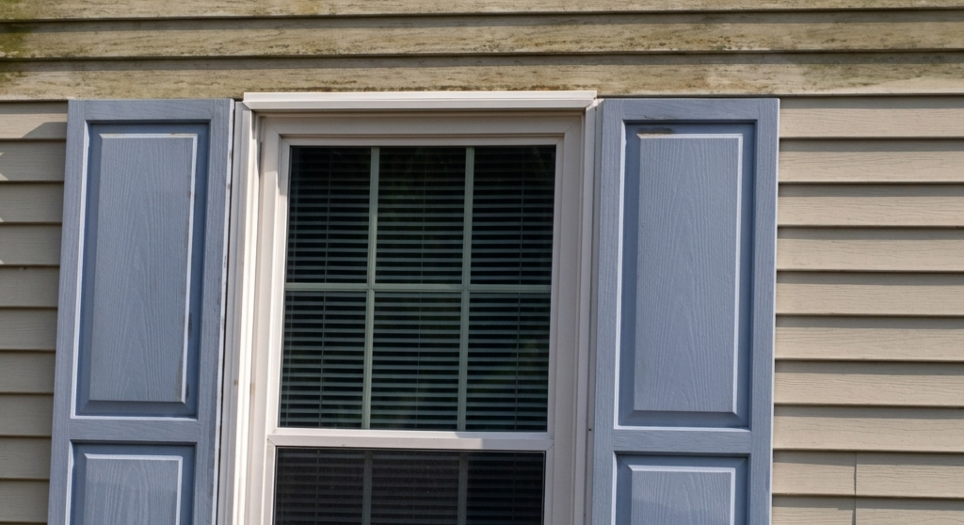 Window with blue shutters and dirty house siding.