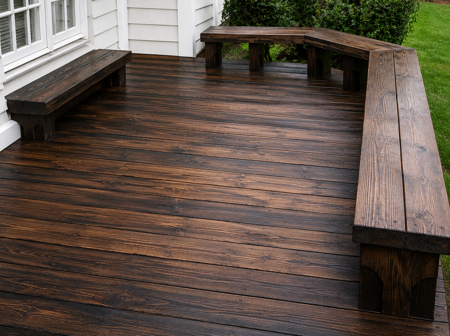 Rain-darkened wooden deck with built-in benches beside a house