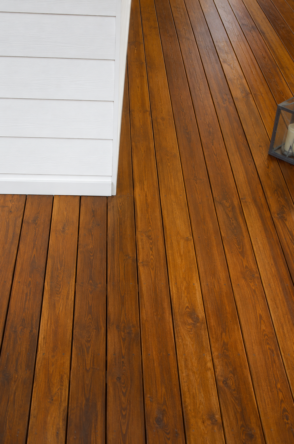 Wooden floorboards beside a white wall and doorway, with a small metal object at the edge.