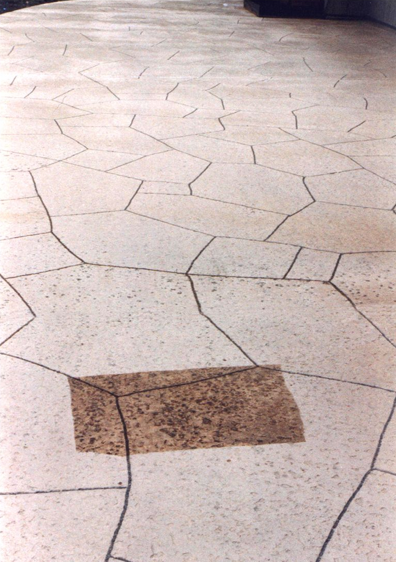 Cracked, pale tile floor with a brown rectangular patch in the foreground