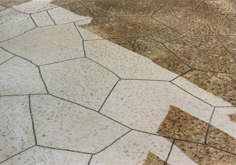 White and tan stone-tile walkway with irregular polygon shapes and speckled brown paving along the edge