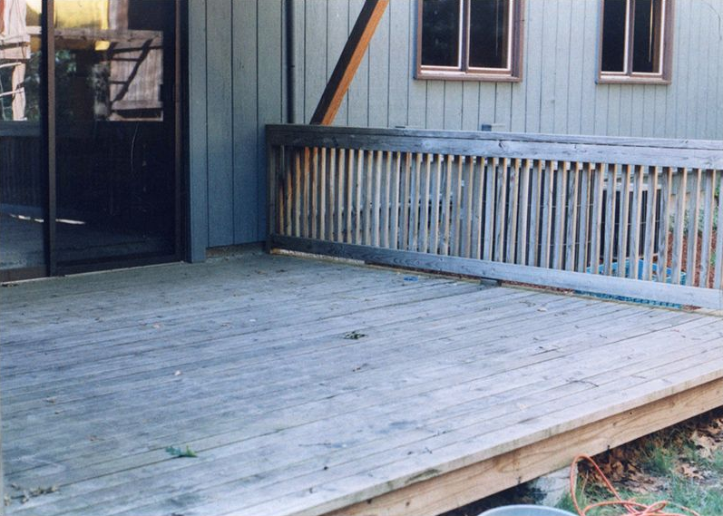 Wooden deck beside a house with a railing and sliding glass door