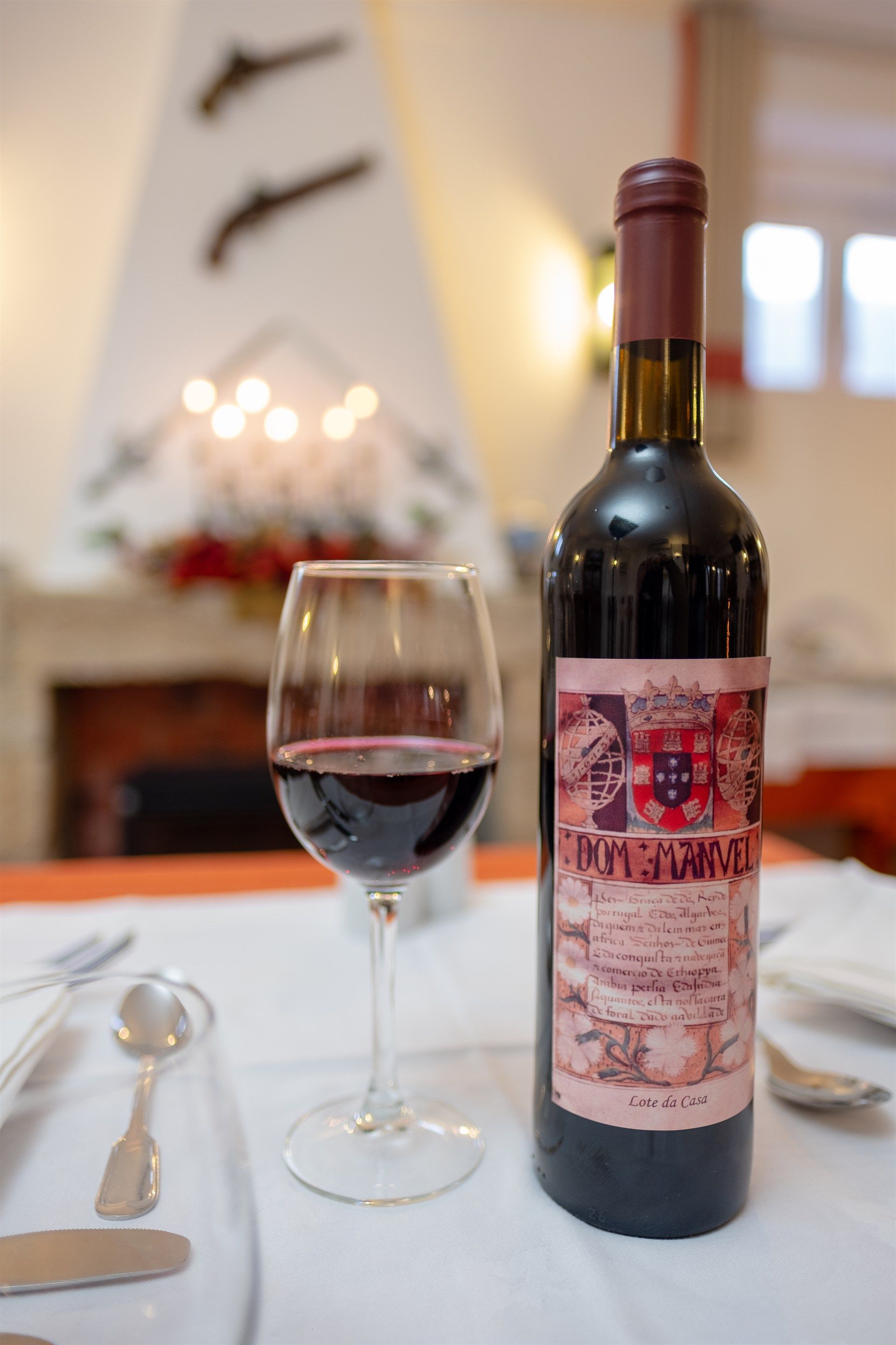 Uma garrafa de vinho está sobre uma mesa ao lado de uma taça de vinho Hotel El Rei Dom Manuel