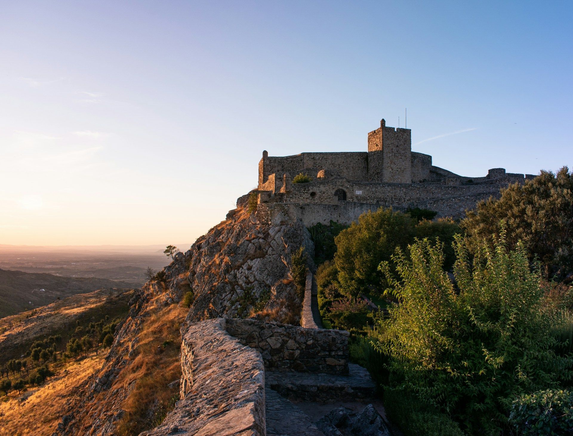 Um castelo está situado no topo de uma colina ao pôr do sol. Marvão 